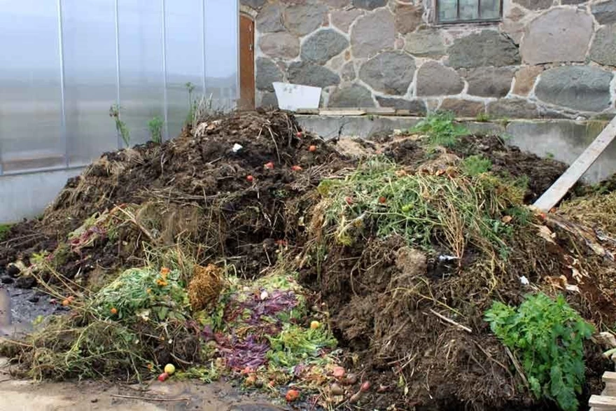 En öppen trädgårdskompost med trädgårdsavfall blir till fin kompostjord.